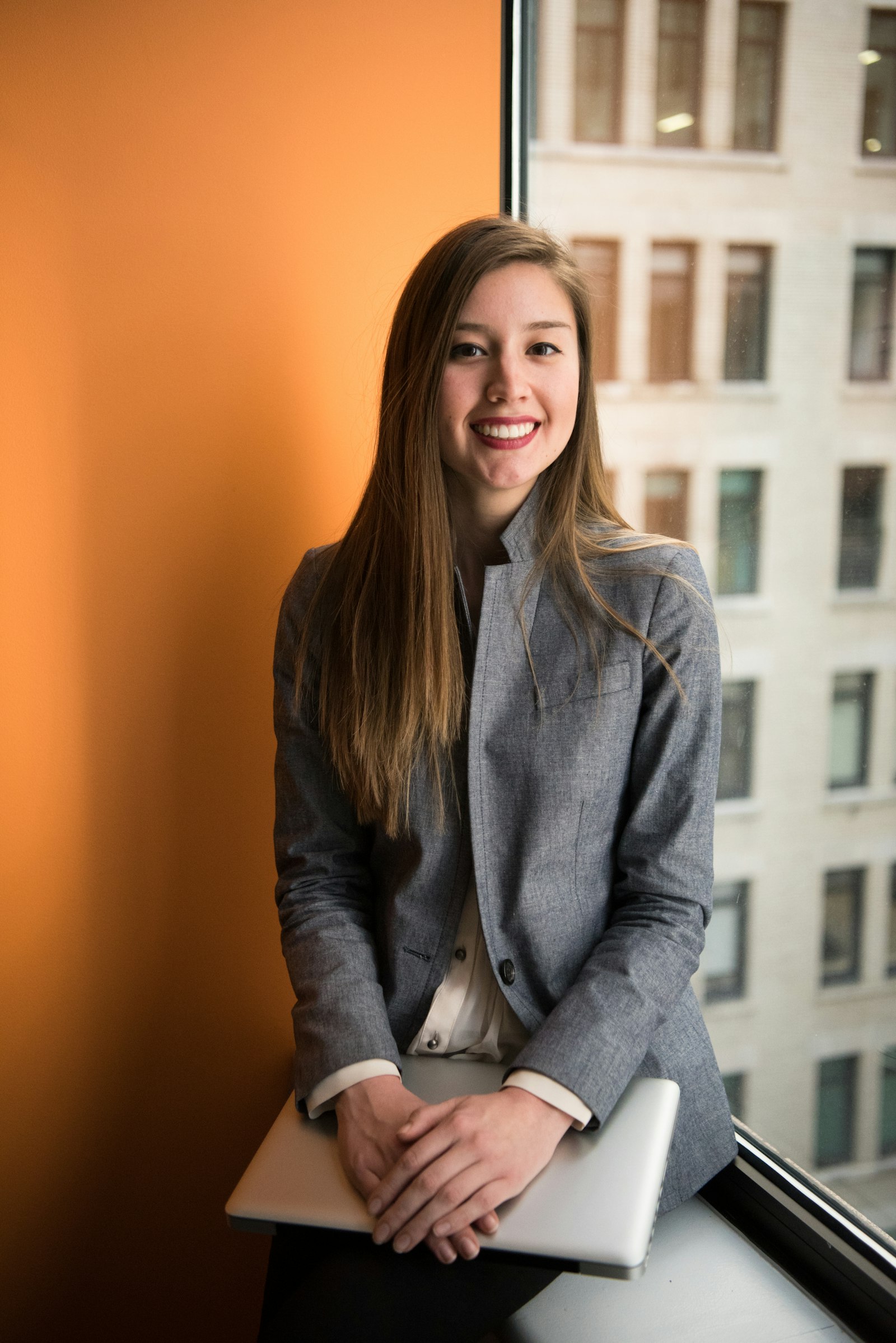 Product manager smiling, holding her laptop by an office window